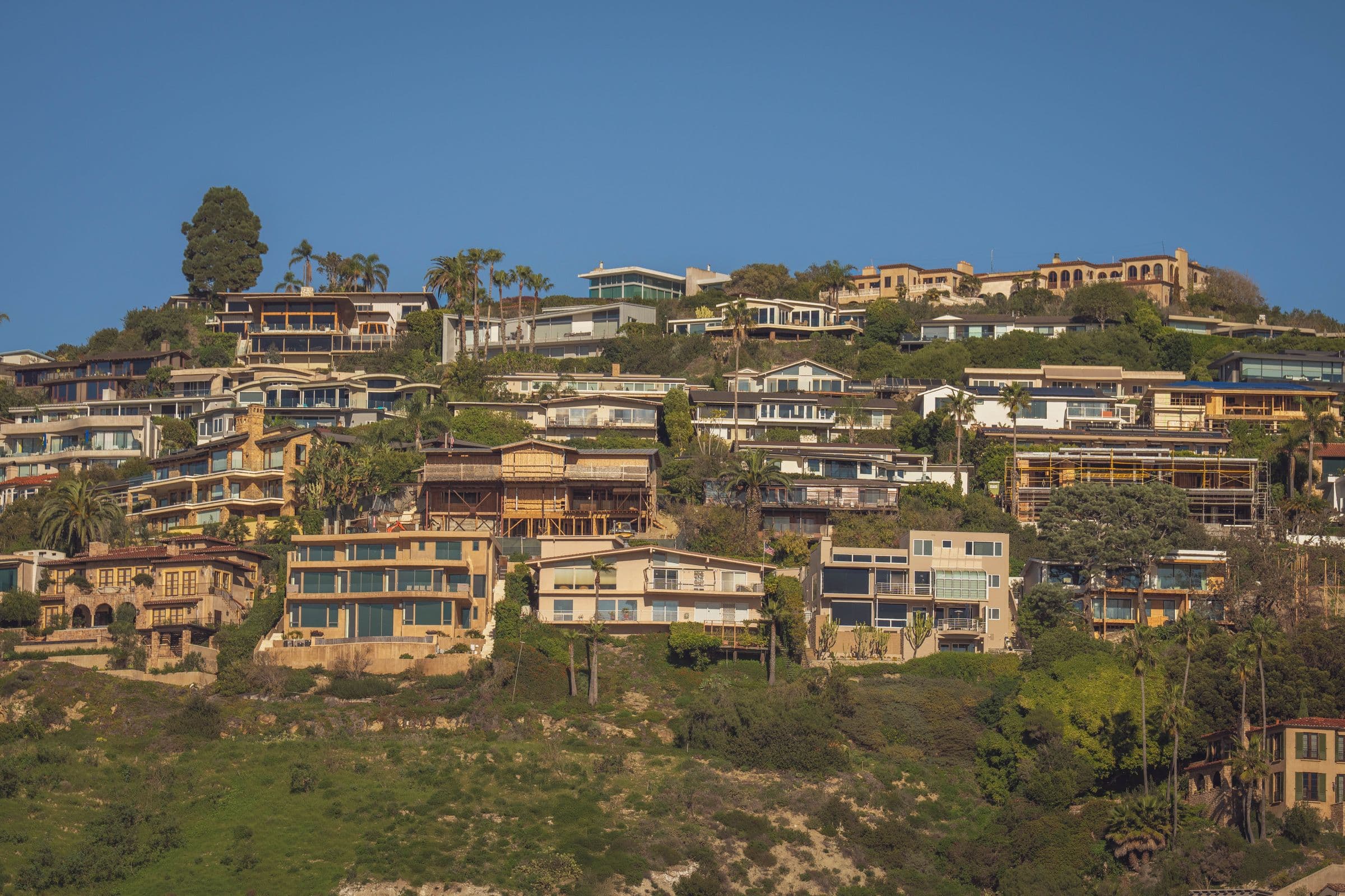 Scenic view of modern hillside homes with lush greenery and blue sky backdrop, the kind of North County setting our movers work in around Hidden Meadows, CA