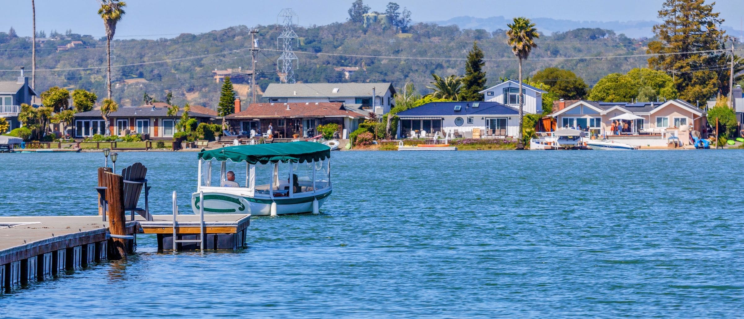 Serene lakeside village featuring homes, pier, and boat on a sunny day, the kind of North County setting our movers work in around Lake San Marcos, CA